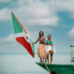 man and woman with burundi flag on boat